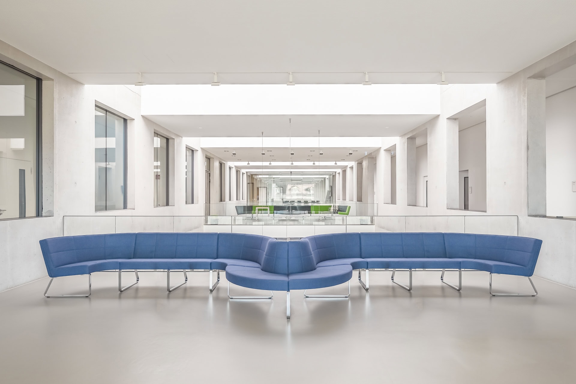 Heller Innenraum von FIT Materialforschung Freiburg mit blauer Sitzlandschaft und langen Blickachsen. Architektur von ArGe Architekten, Leins | Ohnemus, Freie Architekten | Part mbB. Foto: Bertrand Weiss, weissfotografie.com.
