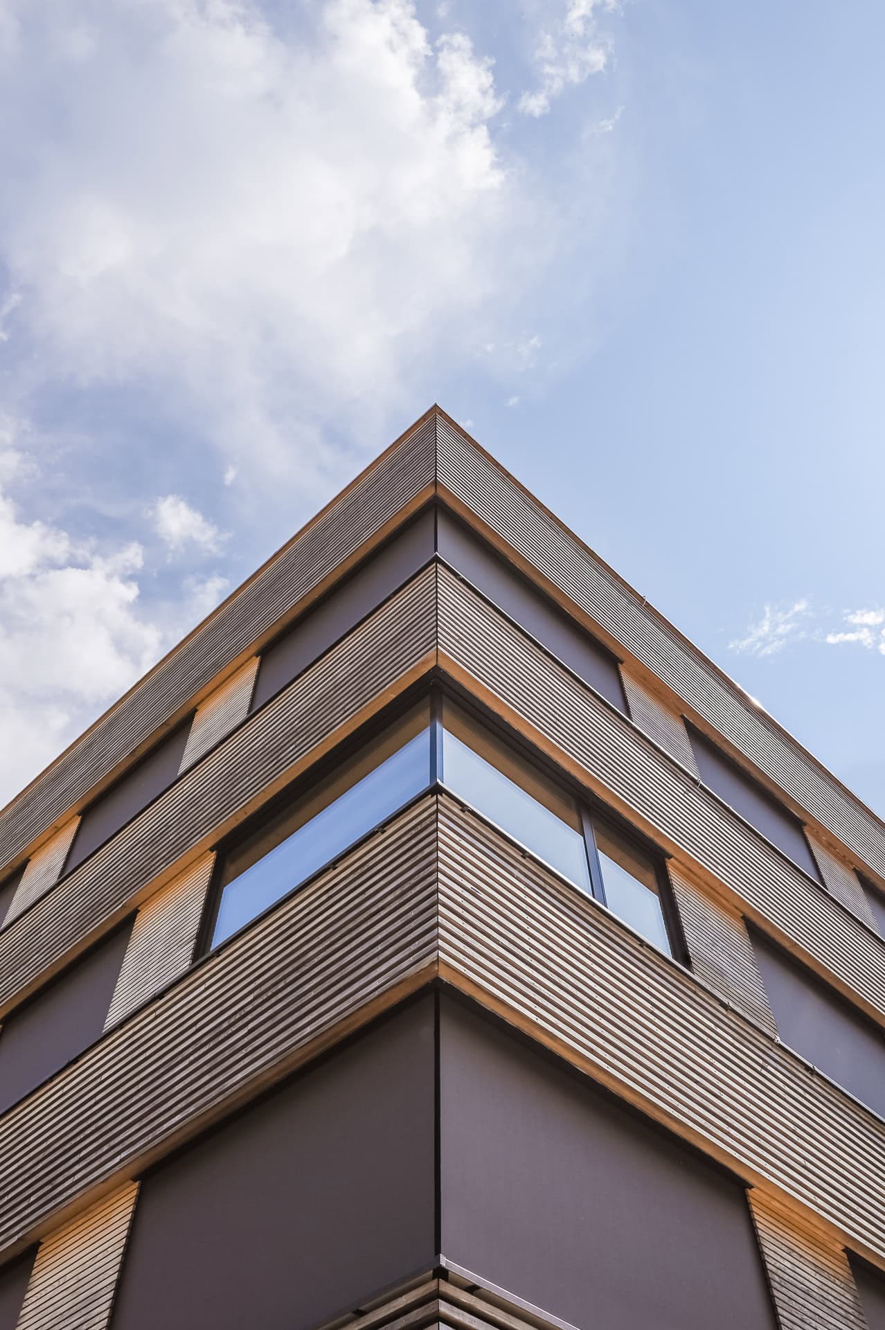 Detailansicht der Gebäudeecke des Forstamts Freiburg mit horizontal gegliederter Holzfassade. Architektur von Stocker Dewes Architekten BDA. Foto: Bertrand Weiss, weissfotografie.com.