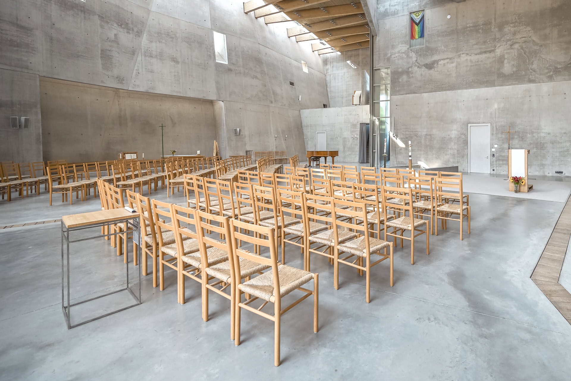 Kirchenraum der Maria-Magdalena-Kirche mit Holzstühlen, Altarbereich und Sichtbetonwänden. Architektur von Kister Scheithauer Gross. Foto: Bertrand Weiss, weissfotografie.com.