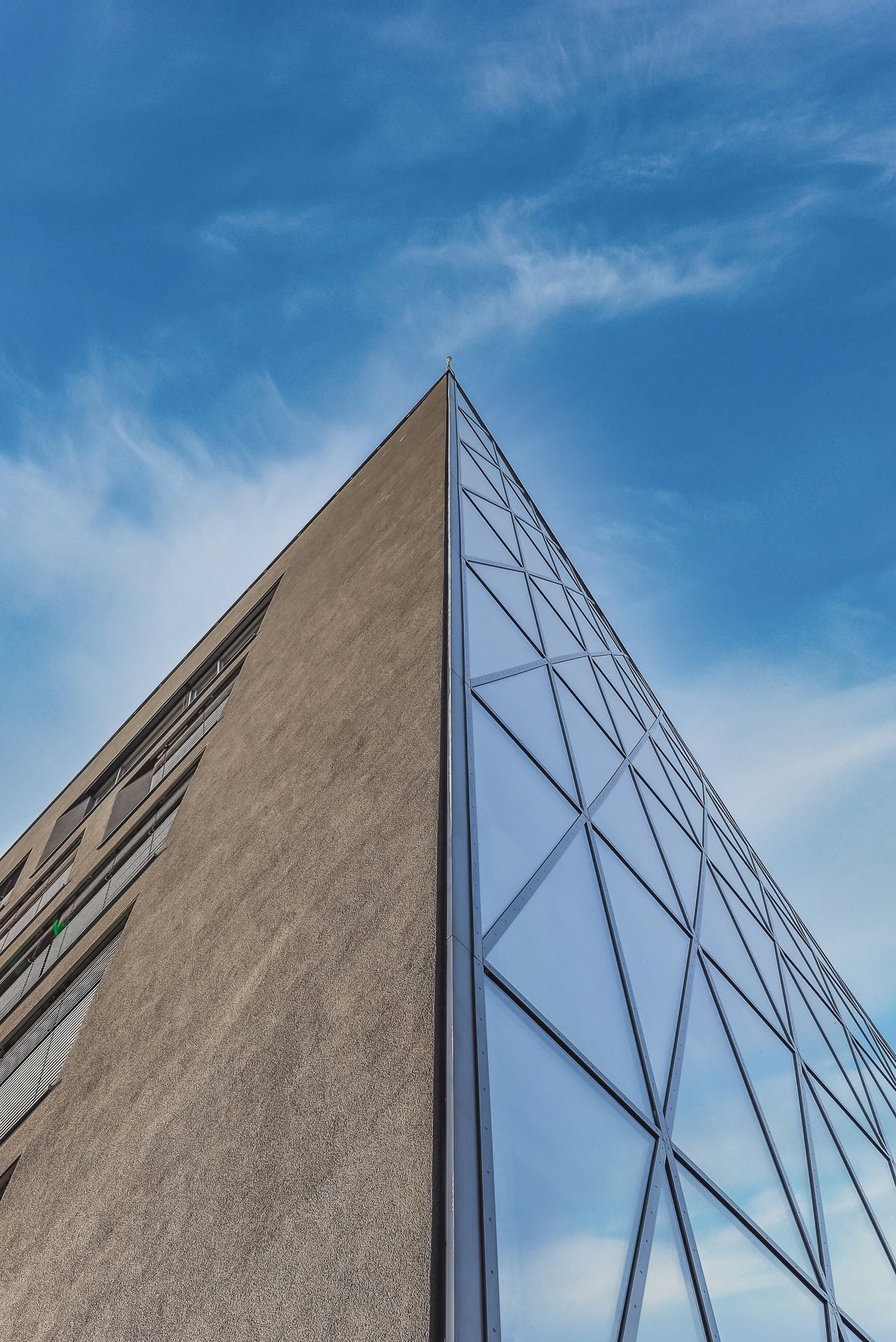 Gebäudeecke von Schnewlin 12 Freiburg mit dunkler Fassade und geneigter Glasfläche vor blauem Himmel. Architektur von hotz+architekten. Foto: Bertrand Weiss, weissfotografie.com.