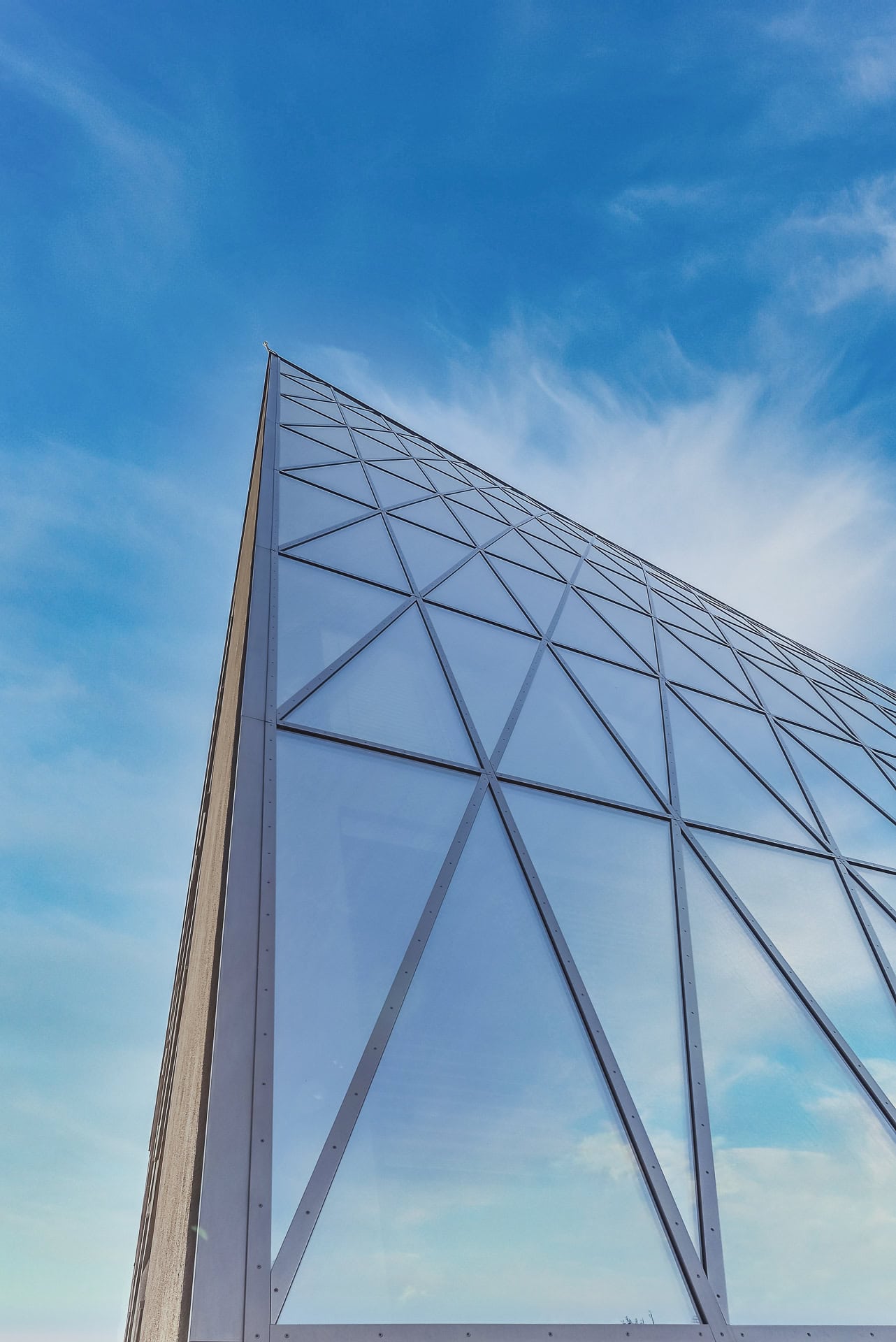 Geneigte Glasfassade von Schnewlin 12 Freiburg mit diagonaler Struktur und Spiegelungen des Himmels. Architektur von hotz+architekten. Foto: Bertrand Weiss, weissfotografie.com.