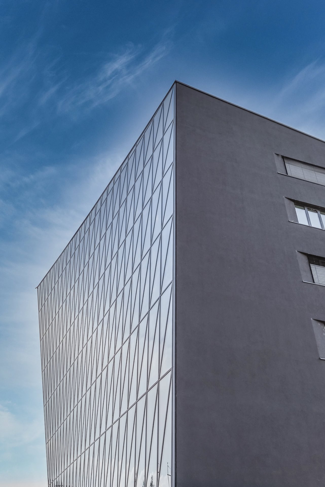 Seitliche Ansicht von Schnewlin 12 Freiburg mit geneigter Glasfassade und dunkler Gebäudeseite. Architektur von hotz+architekten. Foto: Bertrand Weiss, weissfotografie.com.