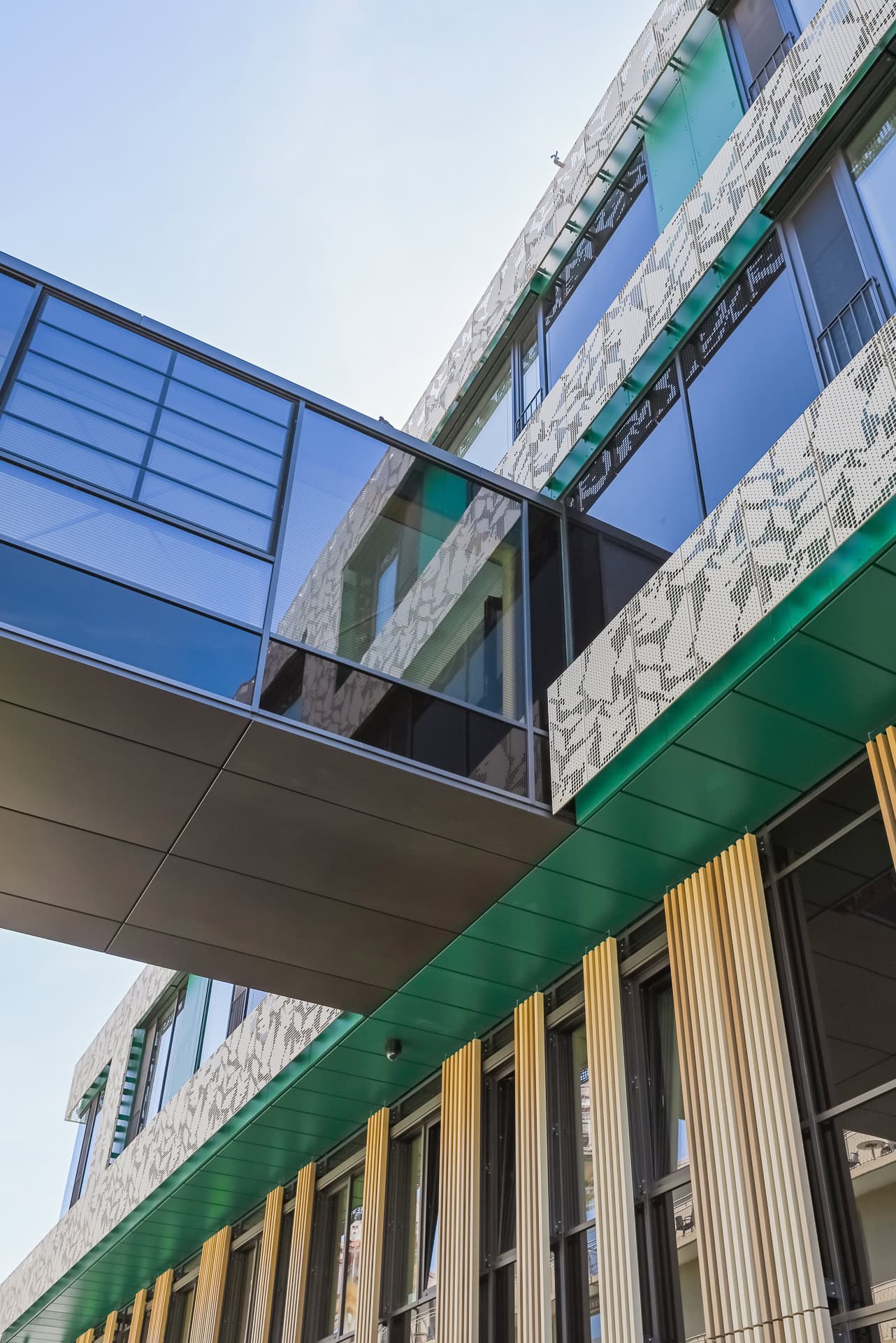 Detail der Kinder- und Jugendklinik Freiburg mit Glasbrücke, perforierter Fassade und grüner Untersicht. Architektur von Heinle, Wischer und Partner. Foto: Bertrand Weiss, weissfotografie.com.
