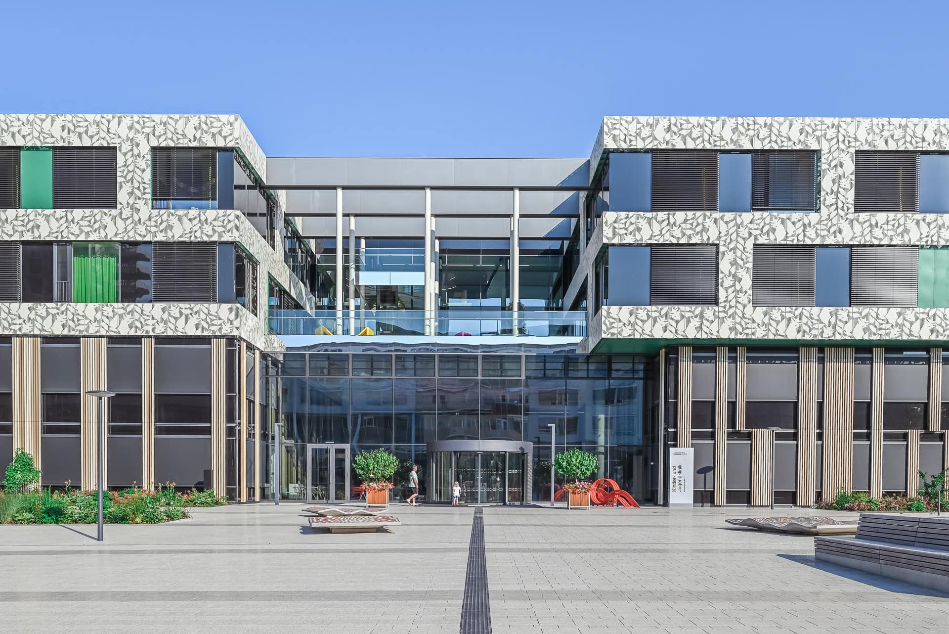 Außenansicht der Kinder- und Jugendklinik Freiburg mit großer Ringskulptur im Park. Architektur von Heinle, Wischer und Partner. Foto: Bertrand Weiss, weissfotografie.com.