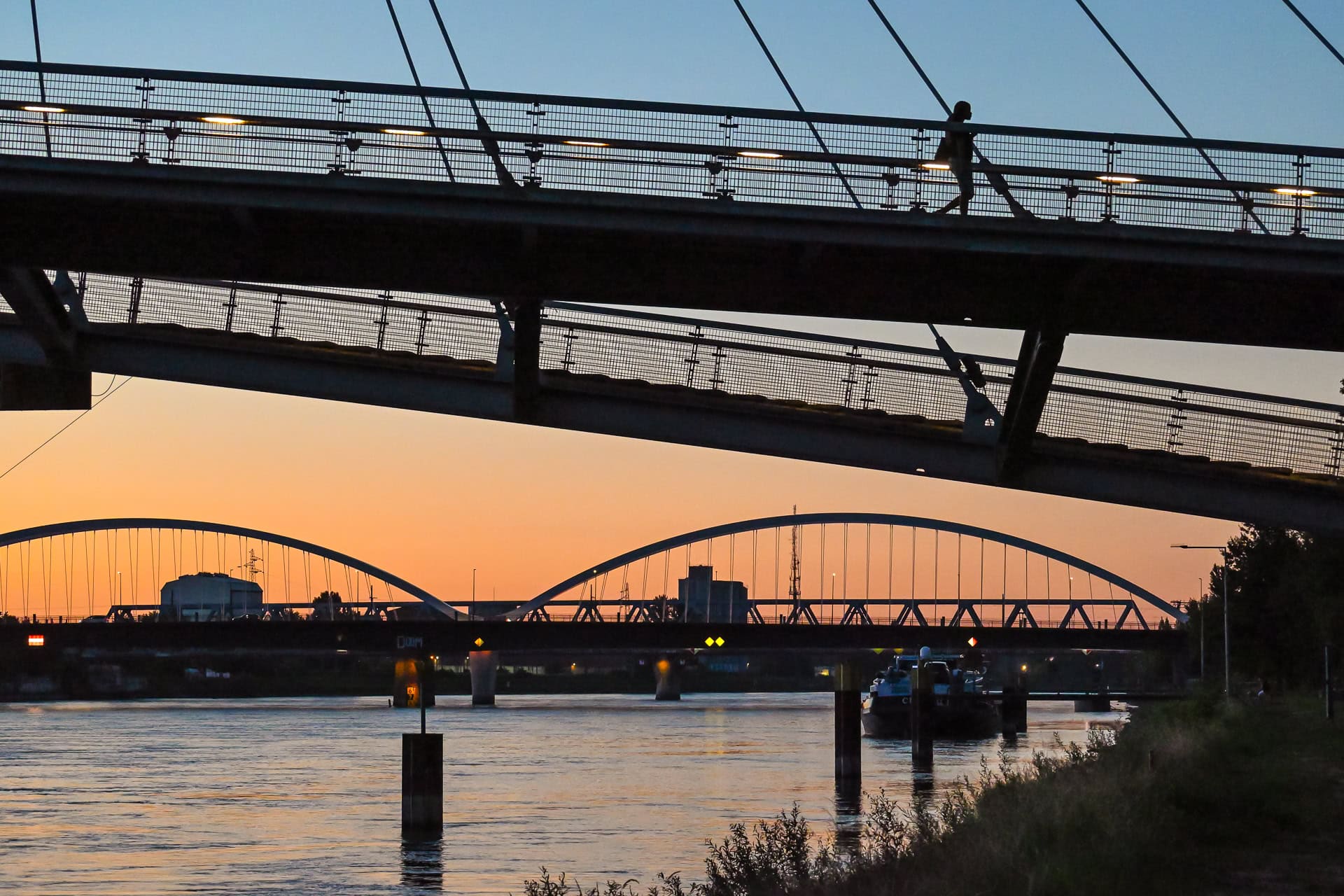 Silhouette der Passerelle des Deux Rives über dem Rhein mit weiterem Brückenbogen im Hintergrund. Architektur von Marc Mimram Architecture & Ingénierie. Foto: Bertrand Weiss, weissfotografie.com.
