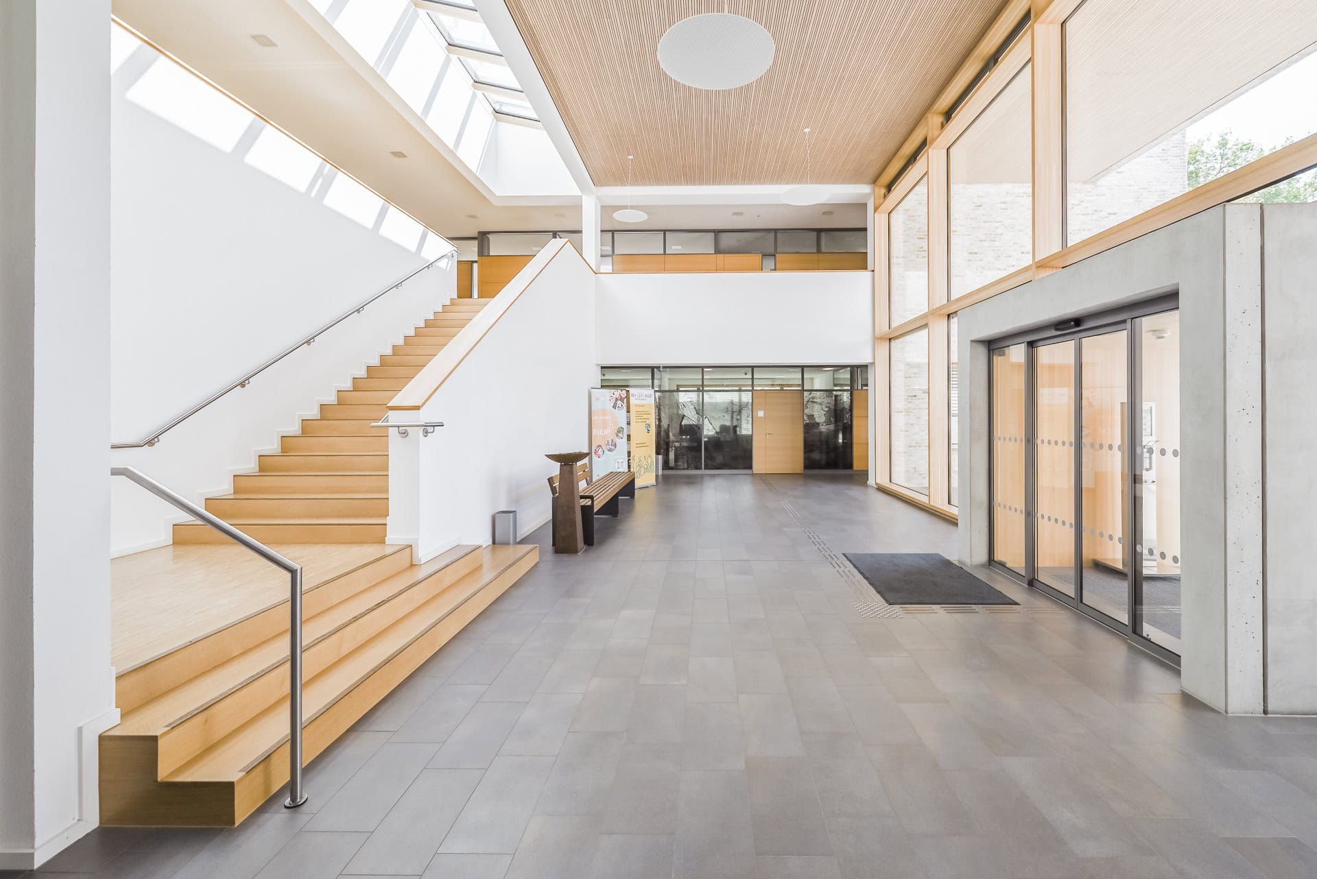 Heller Innenraum des Neuen Rathauses Schallstadt mit Holztreppe, Glasfront und Oberlicht. Architektur von OHO Architekten. Foto: Bertrand Weiss, weissfotografie.com.