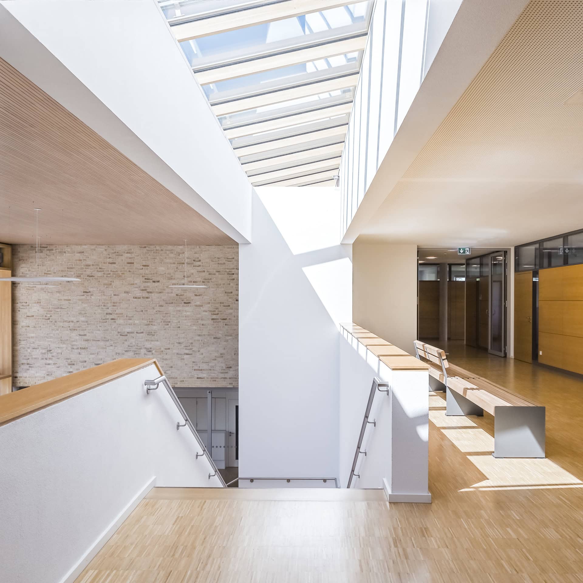 Galeriebereich im Neuen Rathaus Schallstadt mit Oberlicht, Holzoberflächen und Sitzbank. Architektur von OHO Architekten. Foto: Bertrand Weiss, weissfotografie.com.