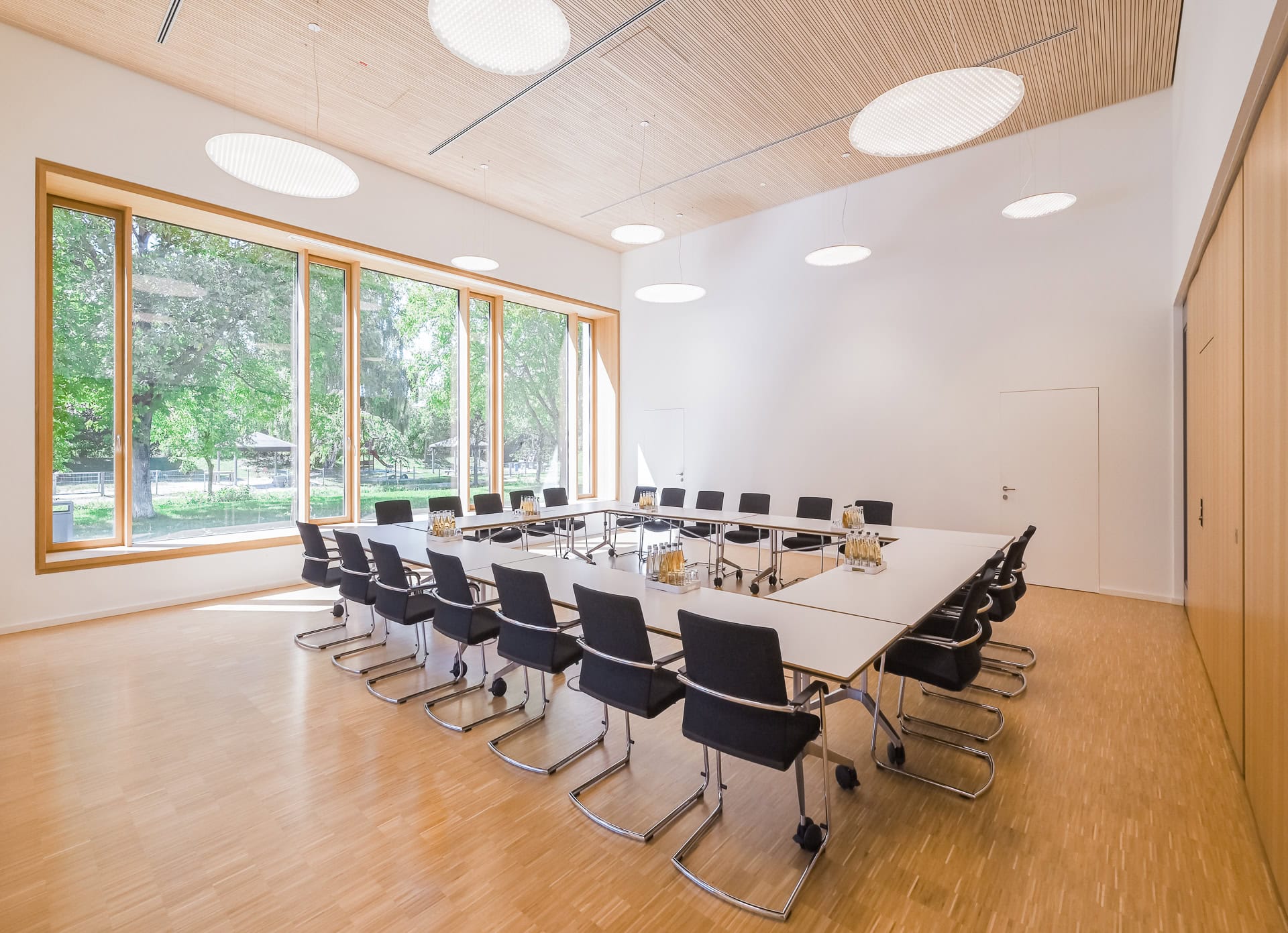 Besprechungsraum im Neuen Rathaus Schallstadt mit Holzdecke, großen Fenstern und Blick ins Grüne. Architektur von OHO Architekten. Foto: Bertrand Weiss, weissfotografie.com.