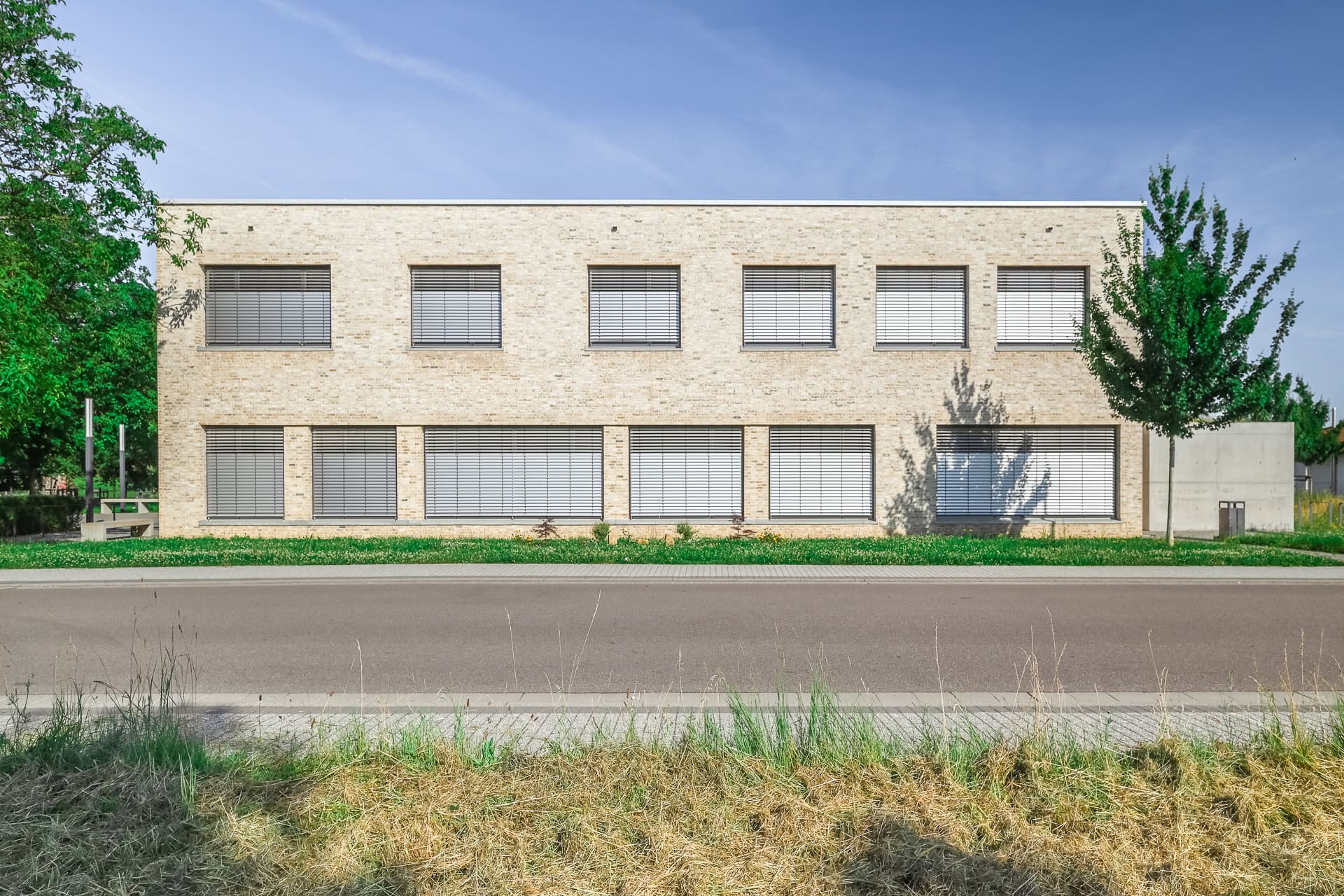 Straßenseitige Fassade des Neuen Rathauses Schallstadt mit hellem Klinker und horizontalen Fensterbändern. Architektur von OHO Architekten. Foto: Bertrand Weiss, weissfotografie.com.
