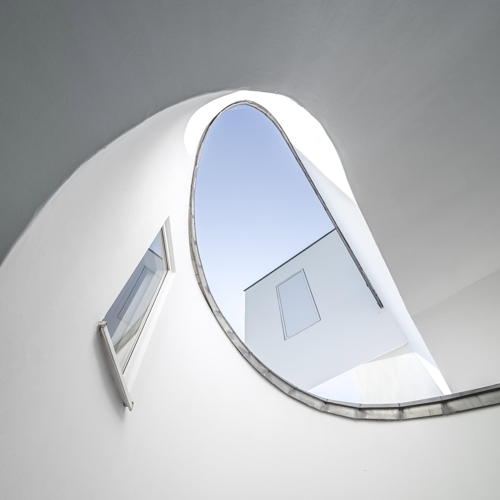 Runder Innenhofblick im Vitra Design Museum mit weißer Wandöffnung, Dachkante und Himmelsausschnitt. Architektur von Frank O. Gehry. Foto: Bertrand Weiss, weissfotografie.com.