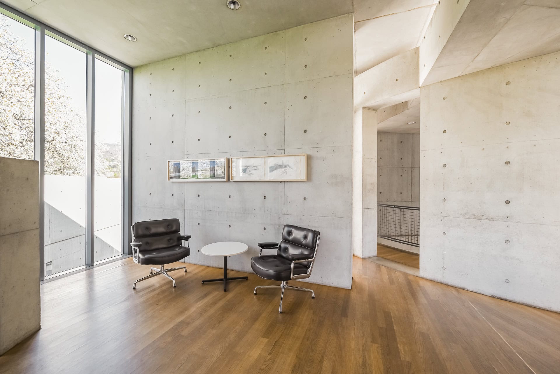 Sitzbereich im Vitra Konferenzpavillon mit Sichtbetonwand, Ledersesseln und Tageslicht. Architektur von Tadao Ando. Foto: Bertrand Weiss, weissfotografie.com.