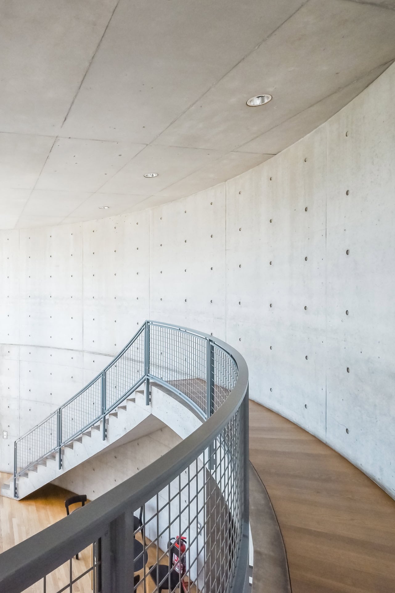Geschwungener Treppenraum im Vitra Konferenzpavillon mit Sichtbetonwand und Metallgeländer. Architektur von Tadao Ando. Foto: Bertrand Weiss, weissfotografie.com.