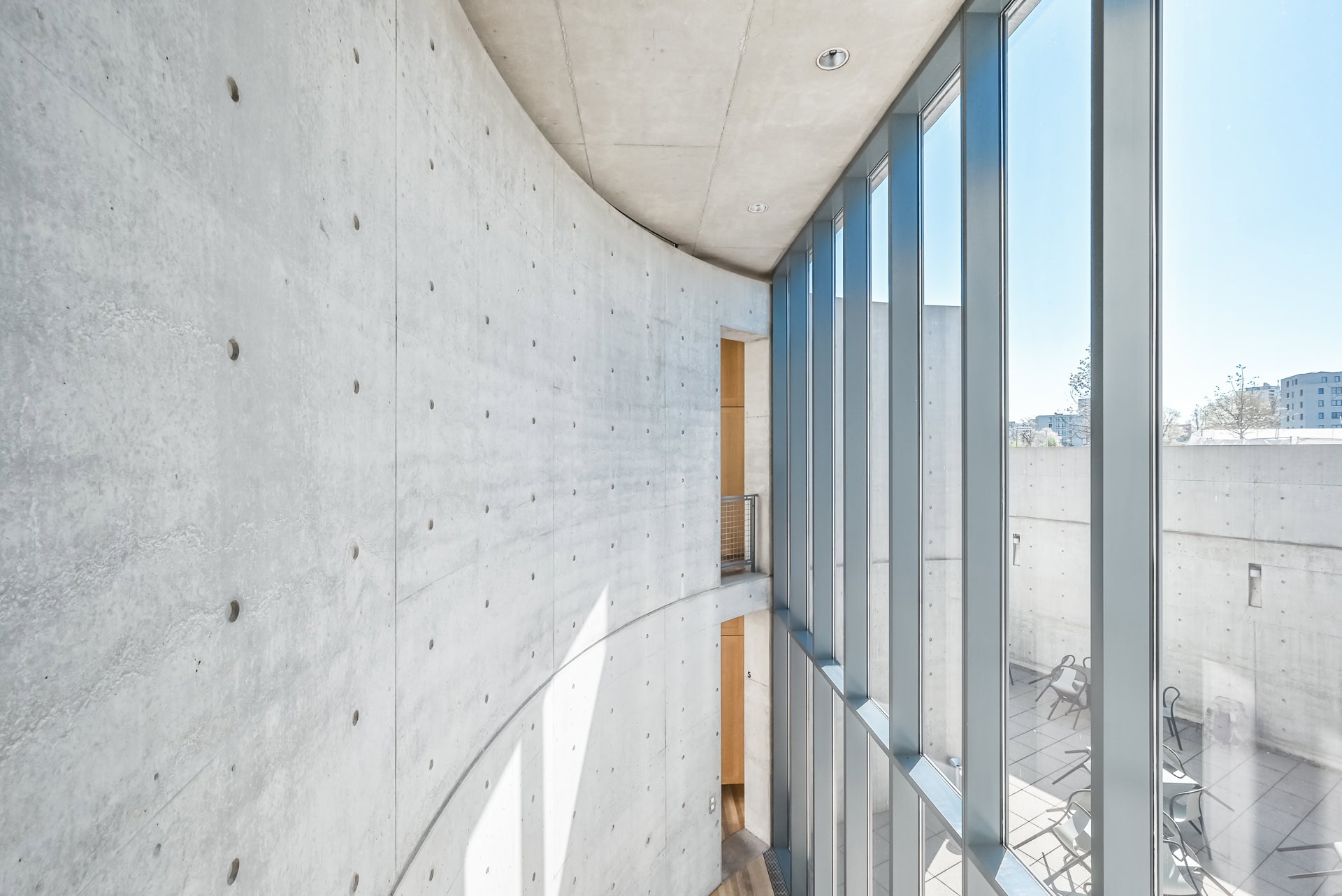 Innenraum des Vitra Konferenzpavillons mit gebogener Betonwand und hohen Glasflächen zum Hof. Architektur von Tadao Ando. Foto: Bertrand Weiss, weissfotografie.com.