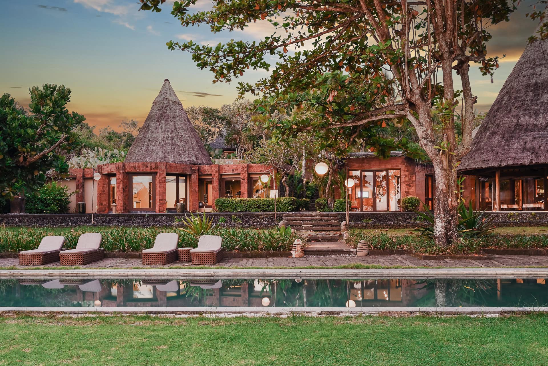 WakaGangga Resort mit Pool, tropischem Garten und reetgedeckten Villen im Abendlicht. Architektur von I Ketut Siandana. Foto: Bertrand Weiss, weissfotografie.com.