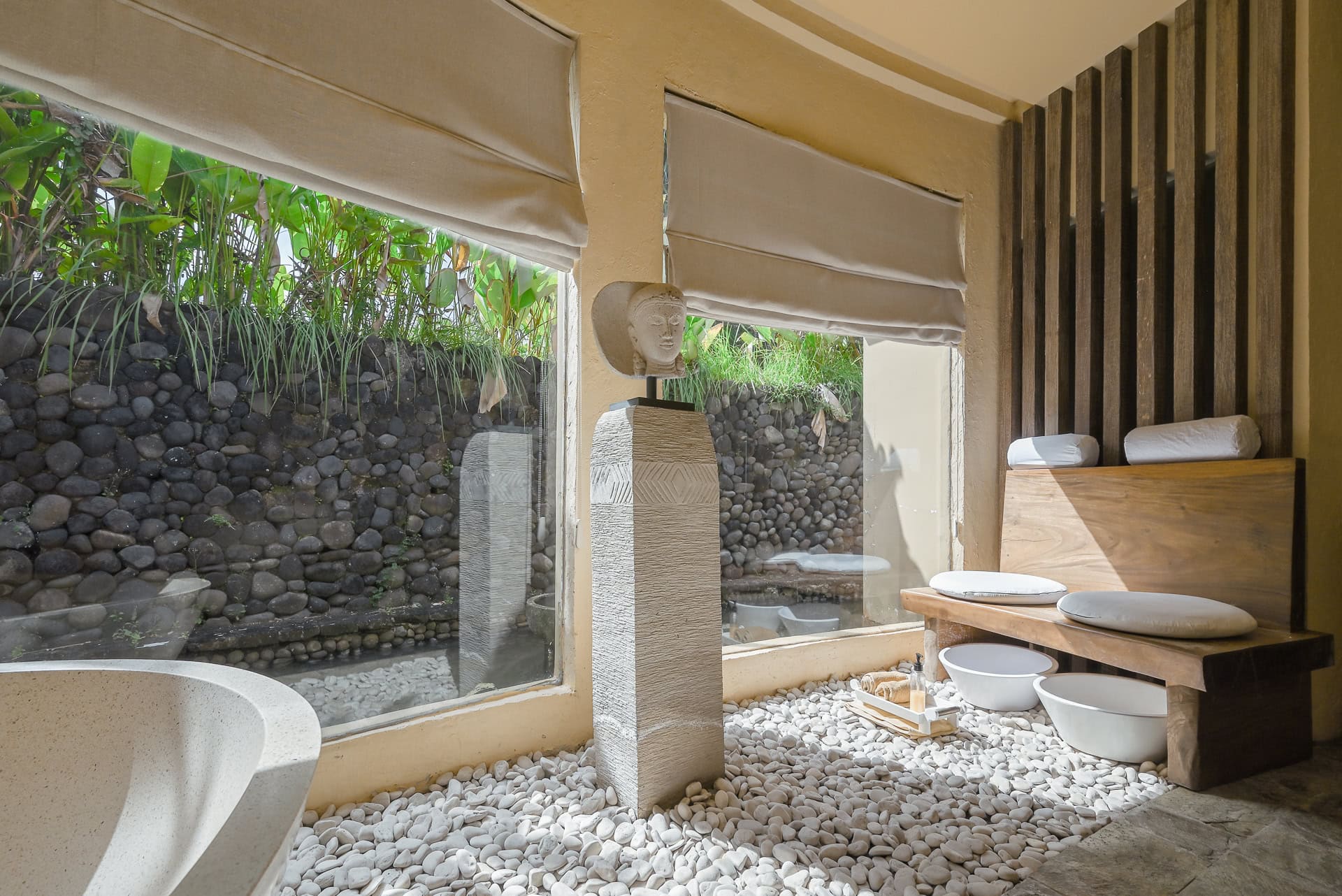 Badebereich mit Naturstein, Holzbank und Blick in einen begrünten Innenhof. Architektur von I Ketut Siandana. Foto: Bertrand Weiss, weissfotografie.com.