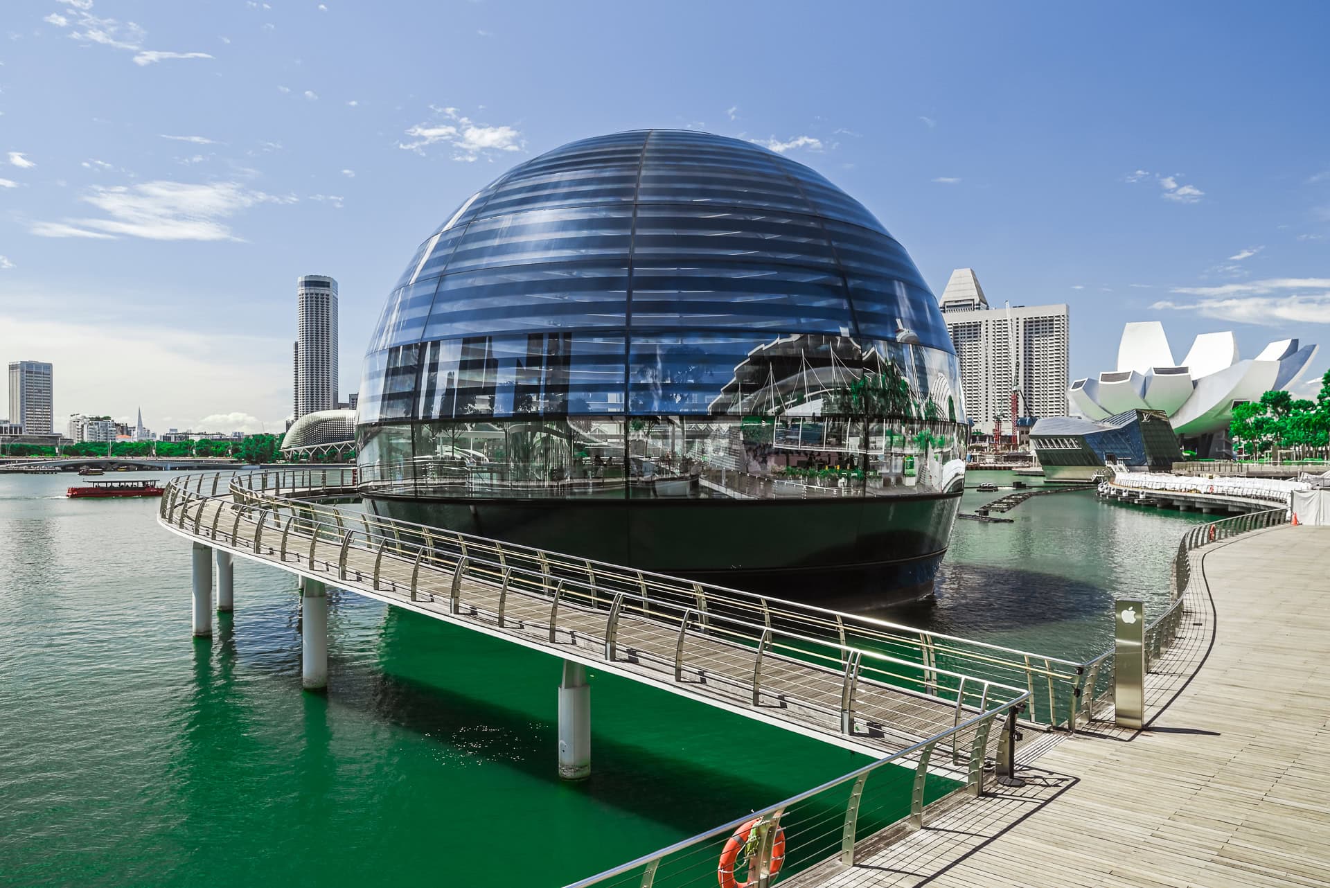 Apple Marina Bay Sands als gläserne Kuppel im Wasser mit ArtScience Museum und Skyline im Hintergrund. Architektur von Foster + Partners. Foto: Bertrand Weiss, weissfotografie.com.