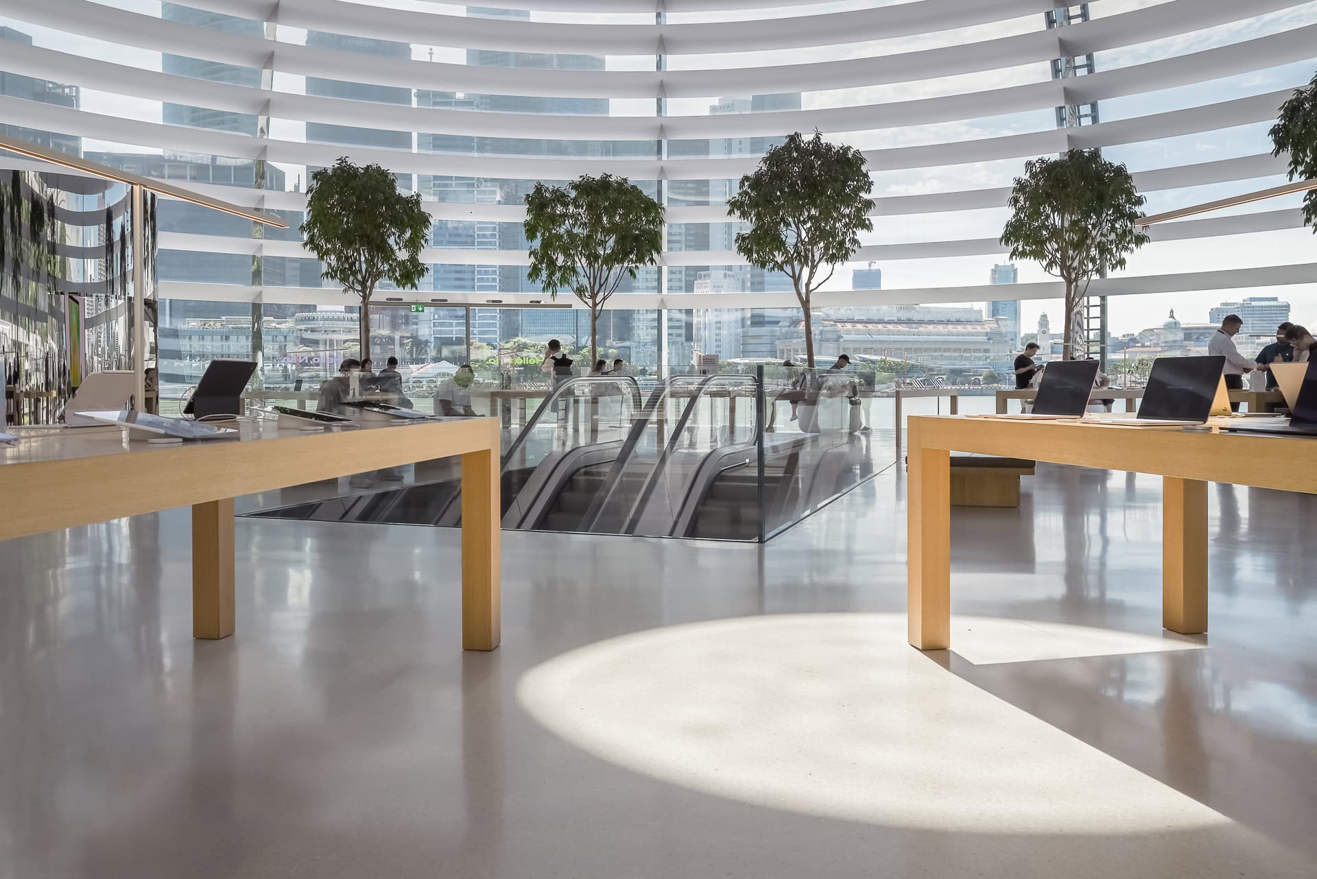 Innenraum des Apple Store mit Holztafeln, Sitzmöbeln und Blick durch die horizontale Lamellenstruktur zur Marina Bay. Architektur von Foster + Partners. Foto: Bertrand Weiss, weissfotografie.com.