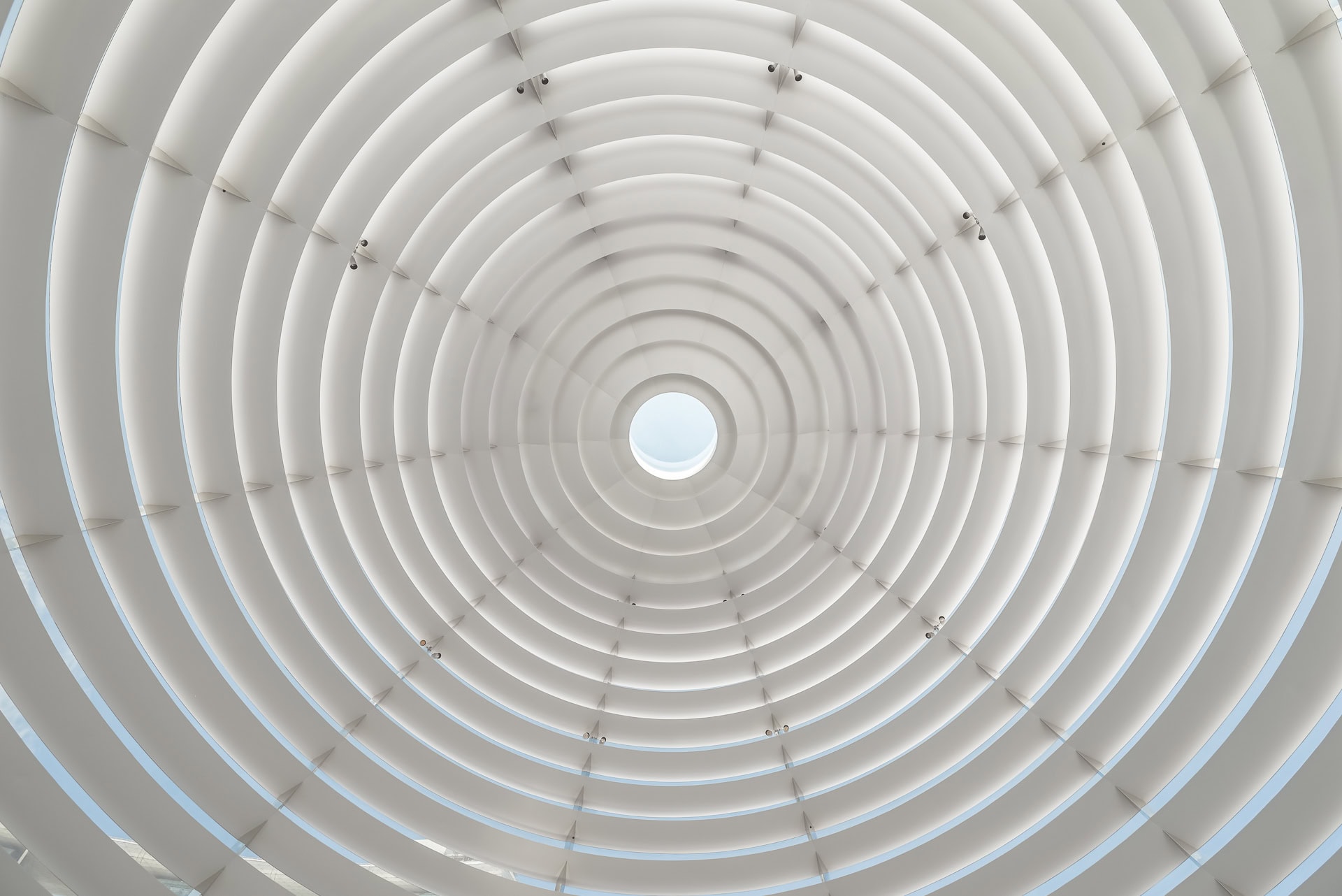 Symmetrischer Blick nach oben in die weiße Kuppelkonstruktion mit zentralem Oberlicht. Architektur von Foster + Partners. Foto: Bertrand Weiss, weissfotografie.com.