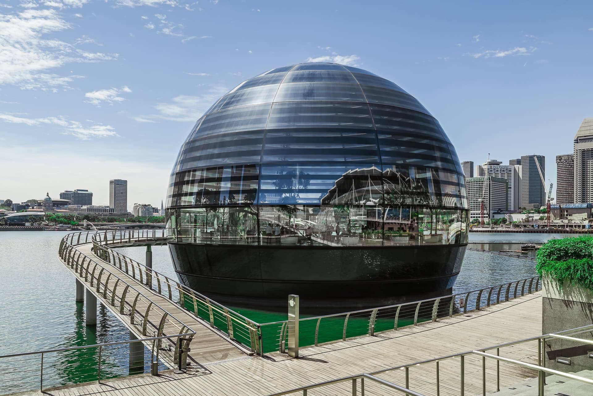 Außenansicht der gläsernen Kuppel im Wasser mit umlaufendem Steg und heller Tageslichtstimmung. Architektur von Foster + Partners. Foto: Bertrand Weiss, weissfotografie.com.
