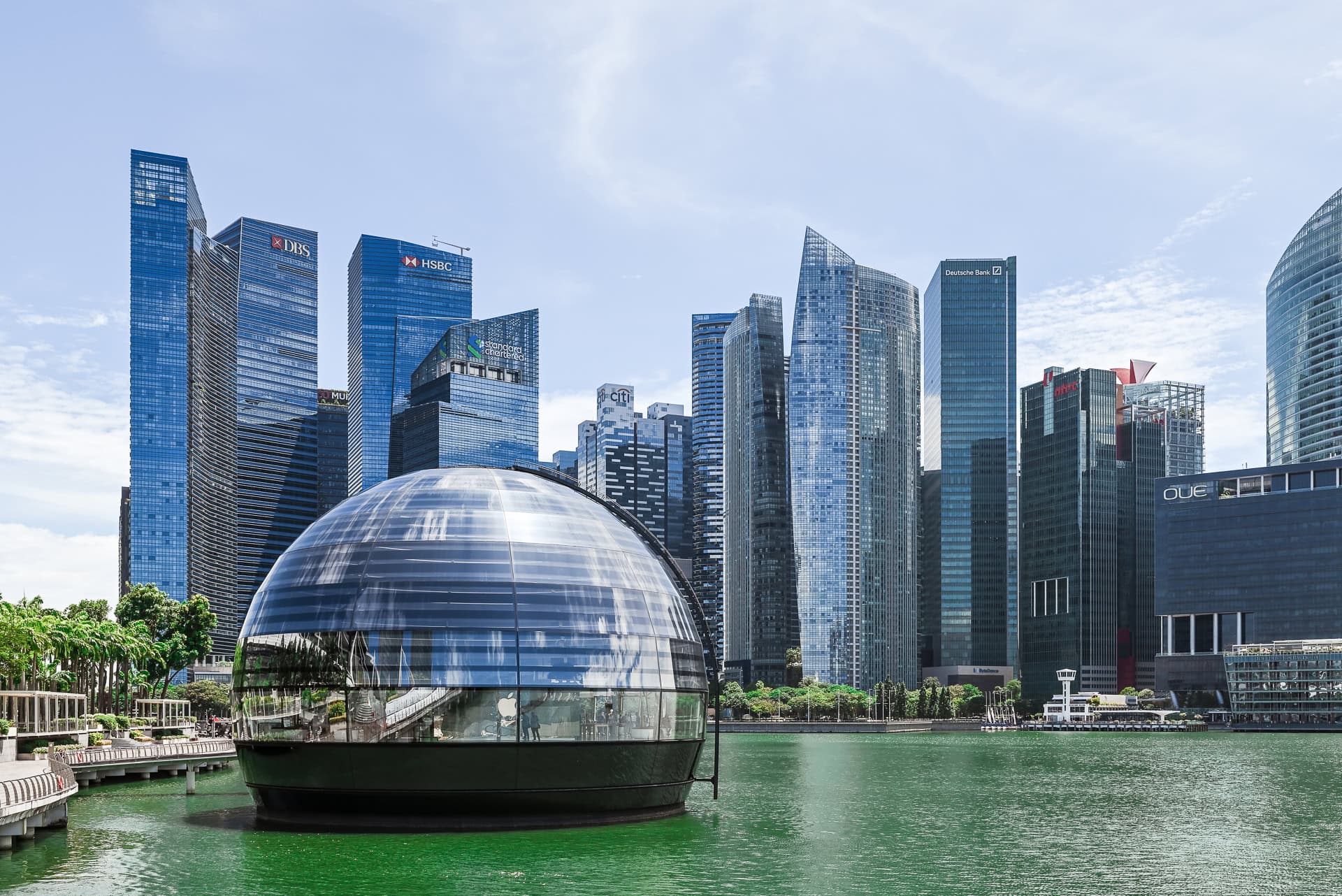 Apple Marina Bay Sands vor der Hochhauskulisse des Finanzviertels mit Wasserfläche im Vordergrund. Architektur von Foster + Partners. Foto: Bertrand Weiss, weissfotografie.com.