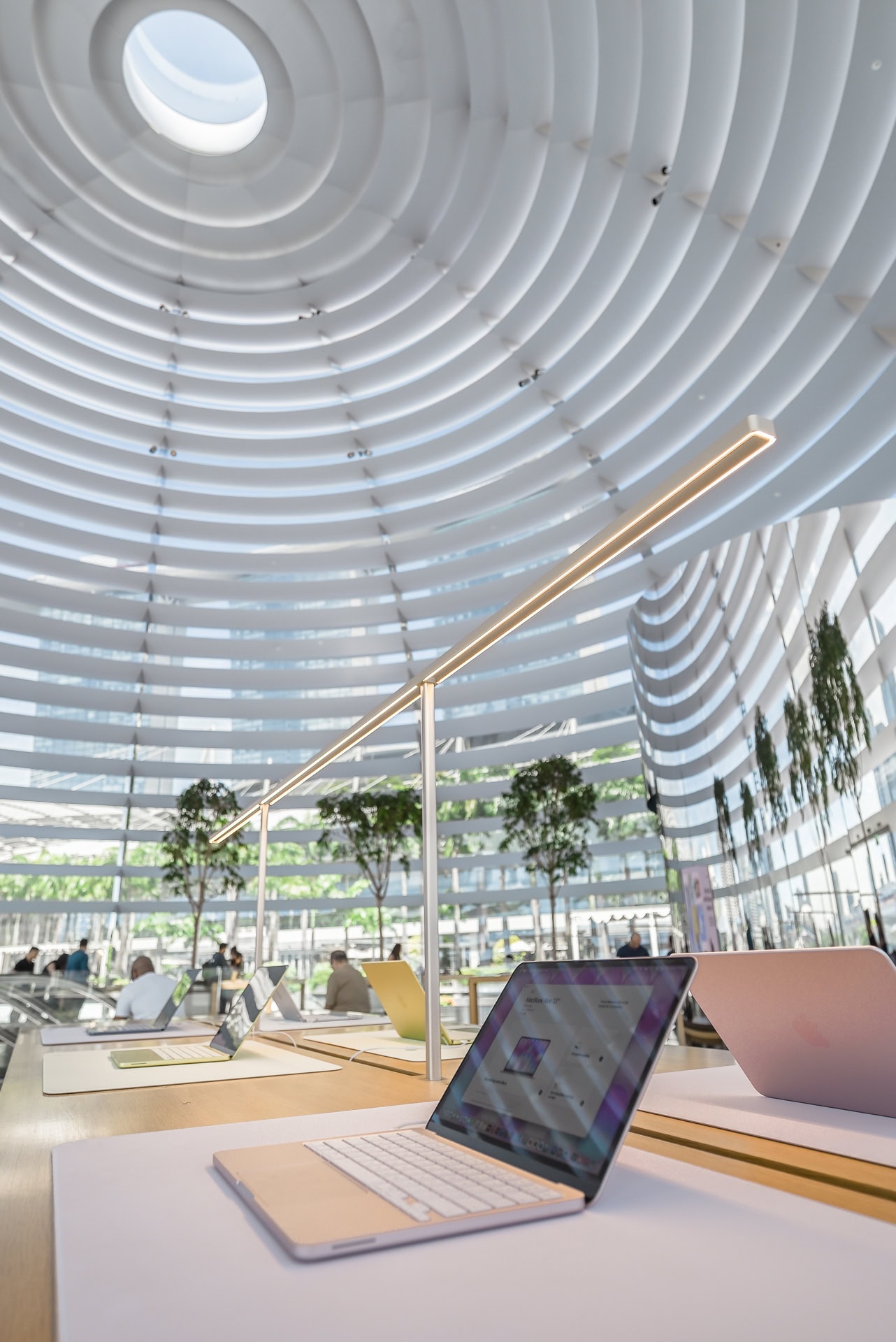 Detail des Innenraums mit beleuchteter Tischleuchte, Produktmöbeln und geschwungener Lamellenstruktur. Architektur von Foster + Partners. Foto: Bertrand Weiss, weissfotografie.com.