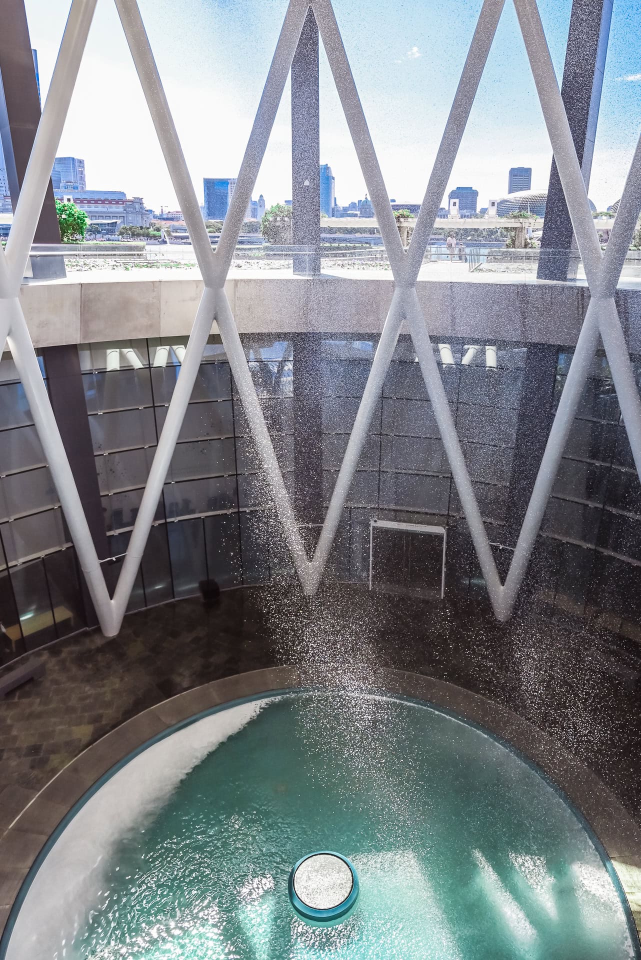 Blick durch die diagonale Tragstruktur auf den zentralen Wasserfall und das Wasserbecken im Inneren. Architektur von Safdie Architects. Foto: Bertrand Weiss, weissfotografie.com.