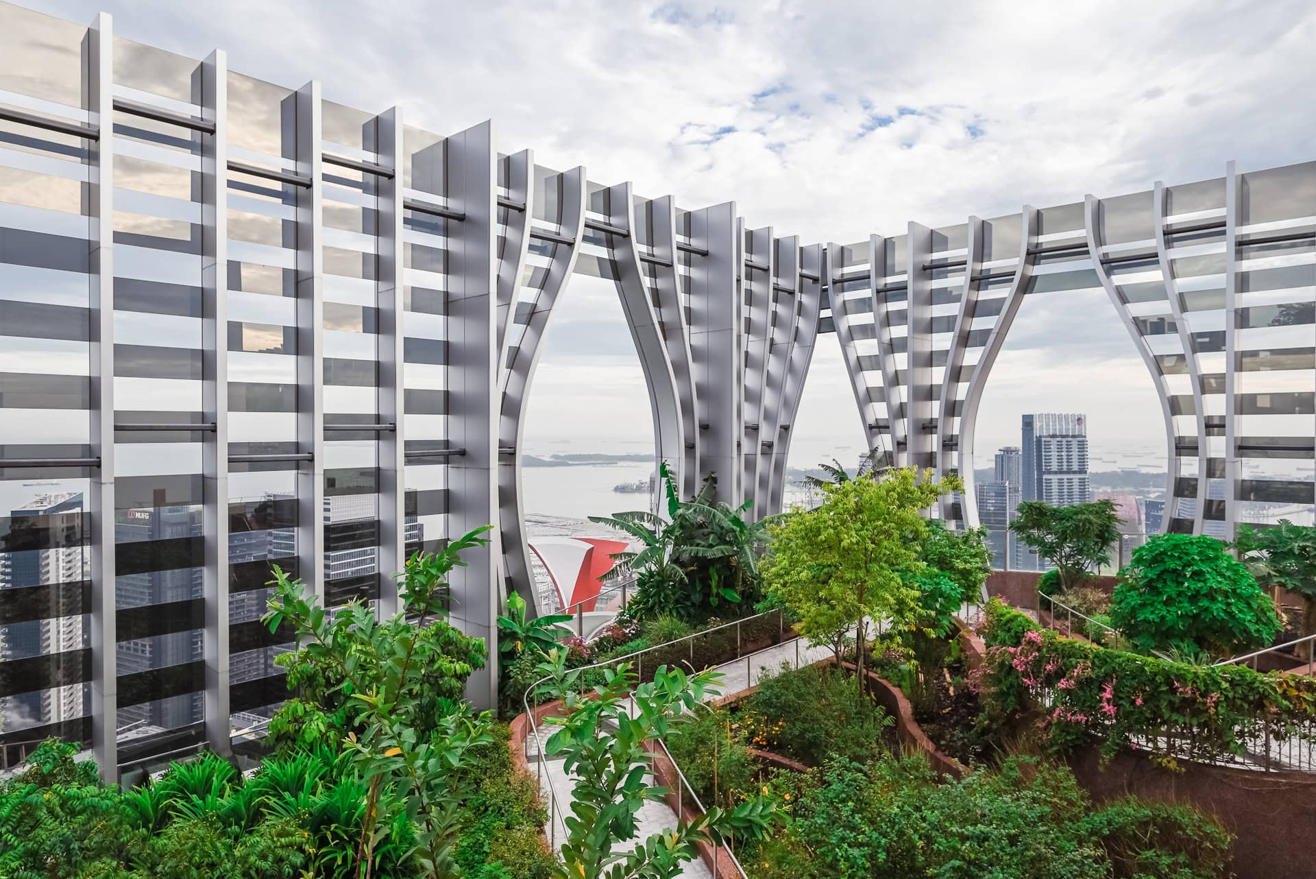Gartenebene mit silbernen Fassadenlamellen, üppiger Vegetation und weitem Blick über die Stadt. Architektur von BIG und CRA. Foto: Bertrand Weiss, weissfotografie.com.