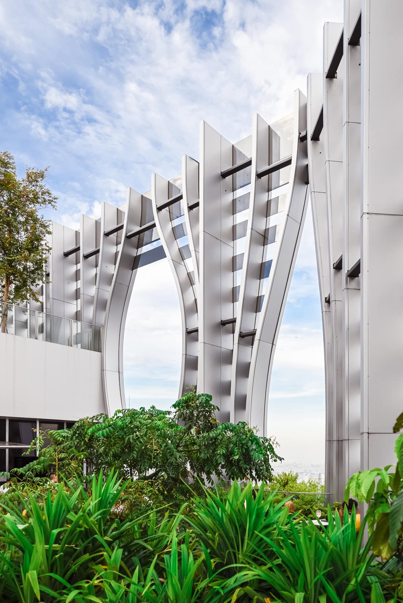 Detailansicht der sich verzweigenden Metallstruktur zwischen Bäumen und dichter Bepflanzung. Architektur von BIG und CRA. Foto: Bertrand Weiss, weissfotografie.com.