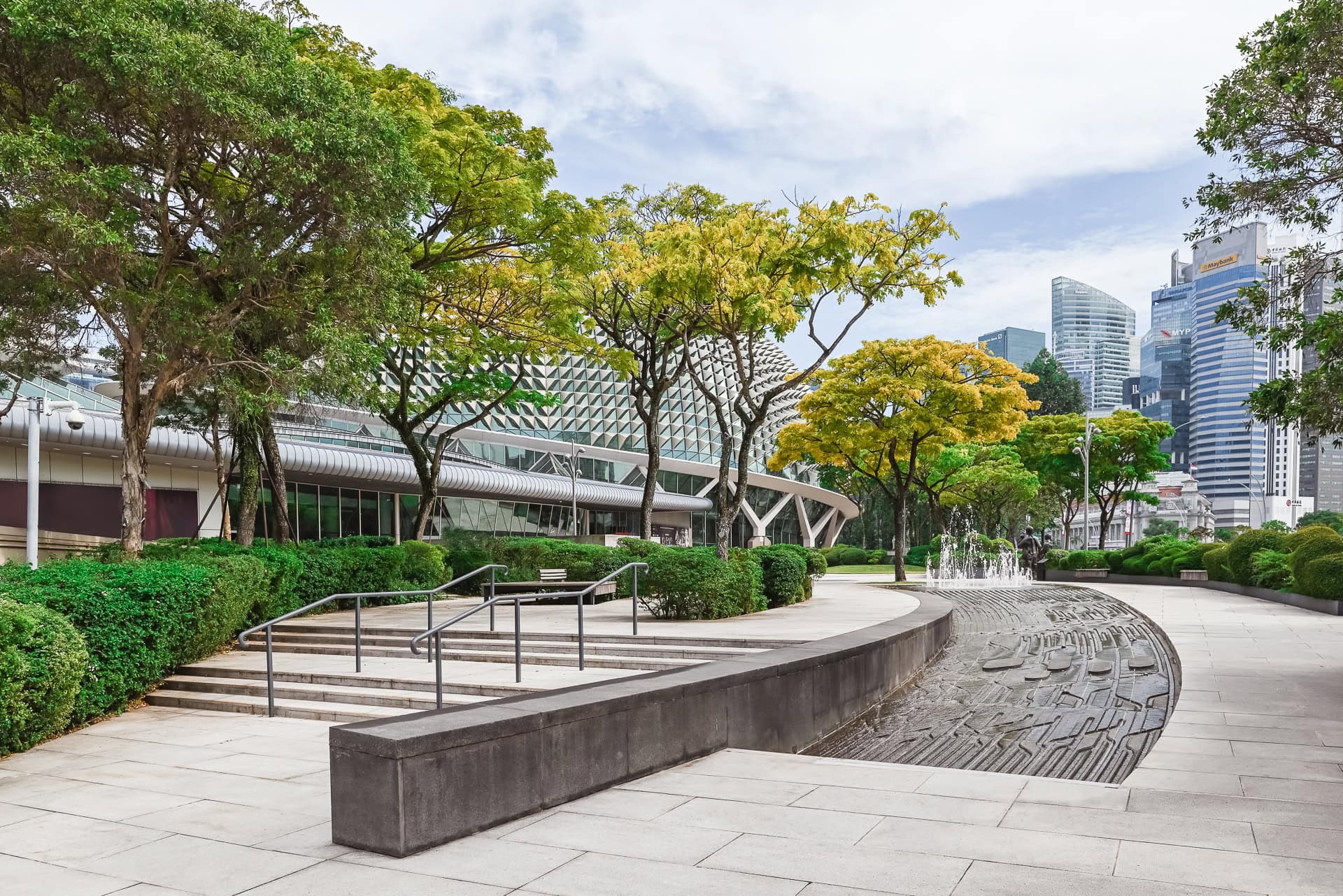 Öffentlicher Platz mit geschwungenem Wasserlauf, Begrünung und Blick auf die Fassaden des Esplanade. Architektur von DP Architects und Michael Wilford & Partners. Foto: Bertrand Weiss, weissfotografie.com.