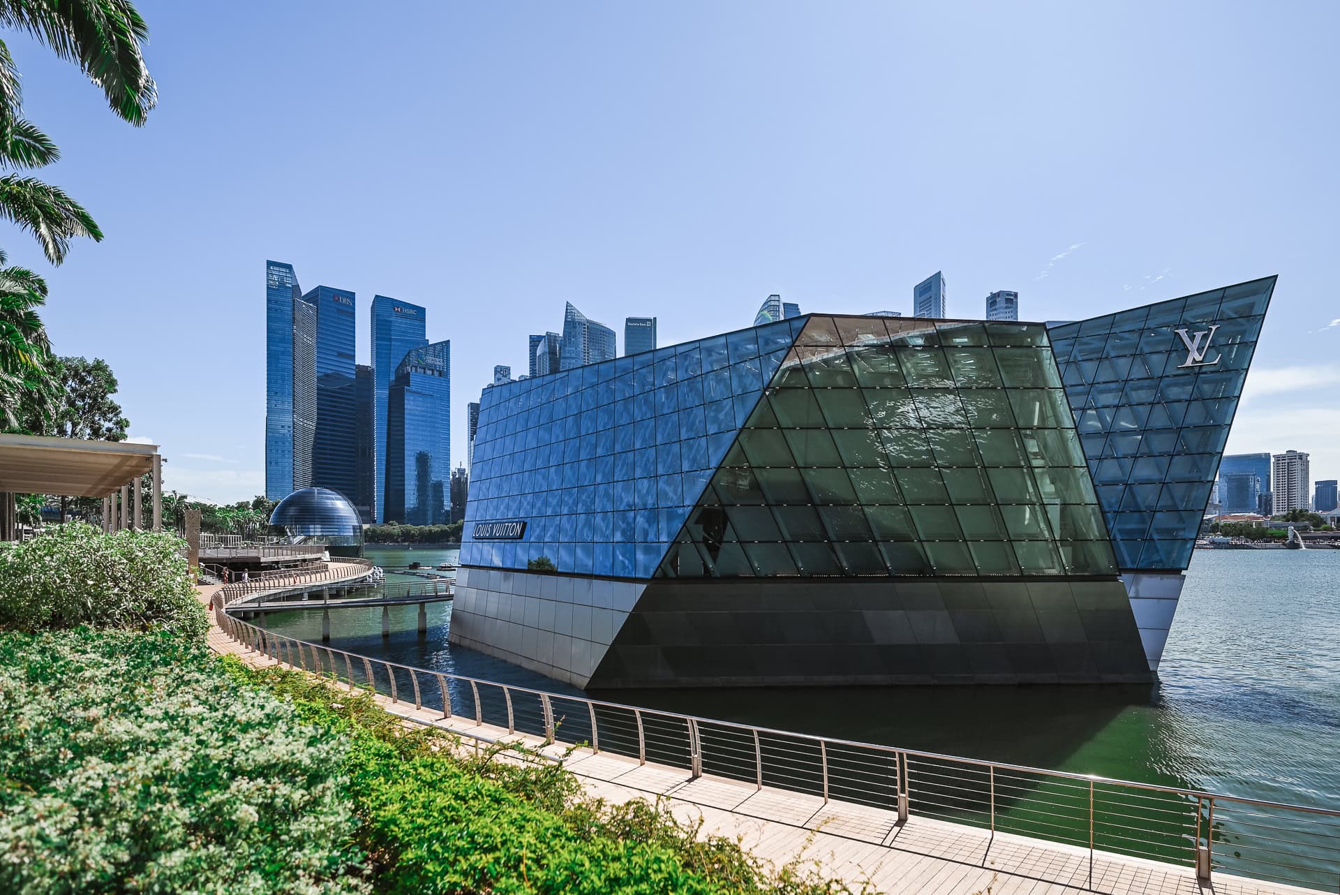 Louis Vuitton Island Maison als gläserner Pavillon im Wasser mit Skyline des Finanzviertels im Hintergrund. Architektur von Safdie Architects. Foto: Bertrand Weiss, weissfotografie.com.