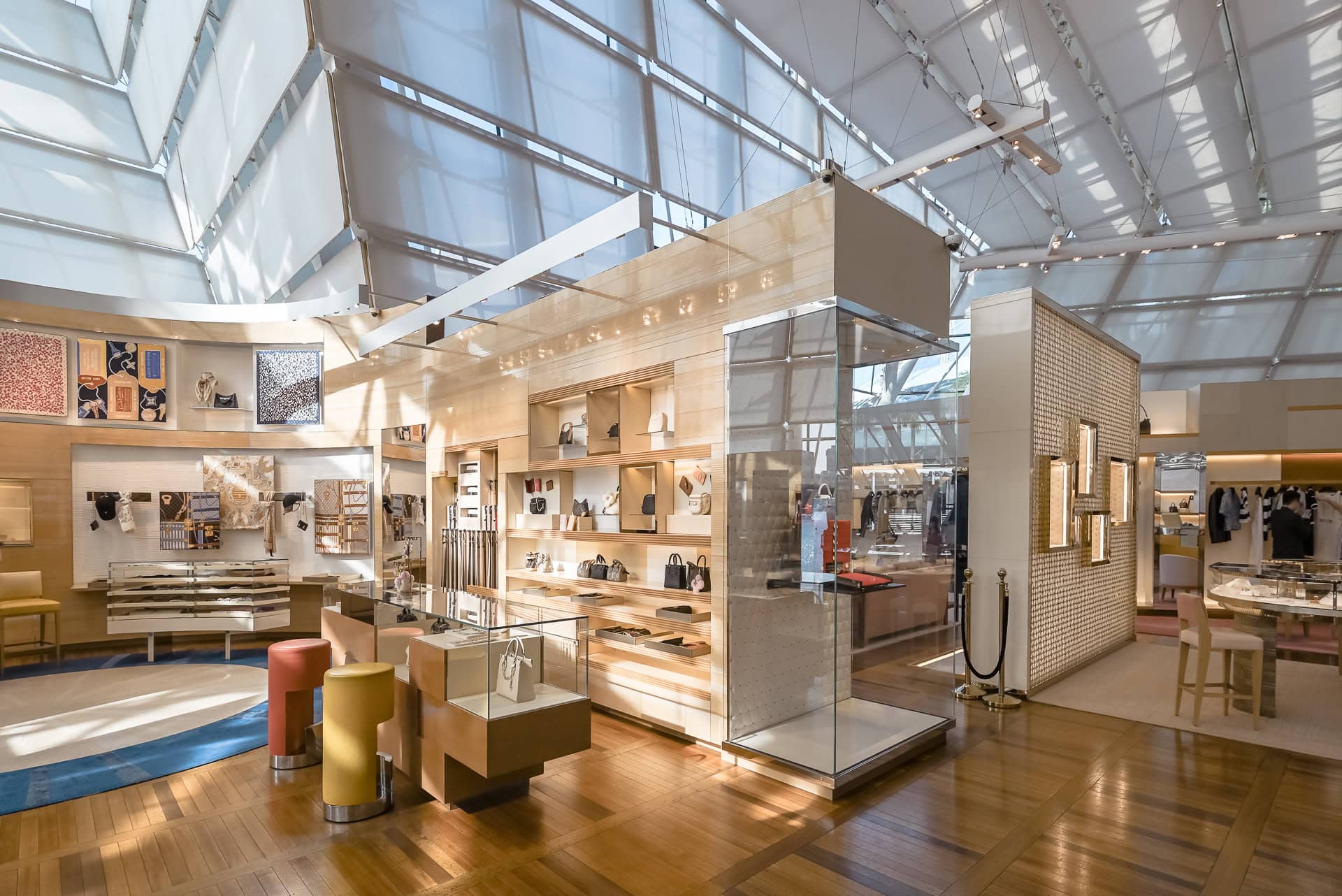Innenraum des Louis Vuitton Island Maison mit hellen Holzeinbauten, Glasfassade und gefiltertem Tageslicht. Architektur von Safdie Architects und Peter Marino Architect. Foto: Bertrand Weiss, weissfotografie.com.
