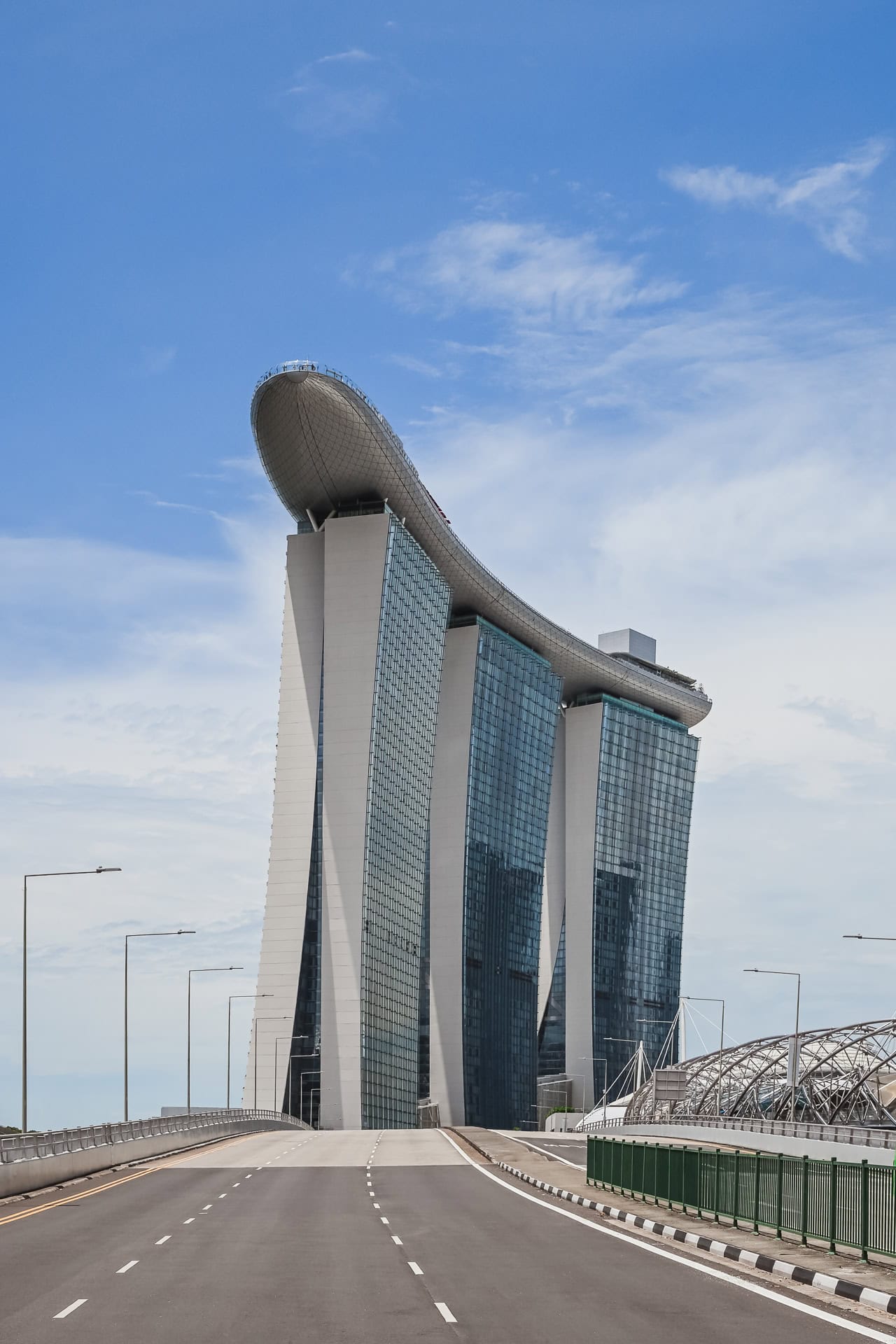 Ansicht des Marina Bay Sands von einer Brücke mit drei Hoteltürmen, SkyPark und klarer Straßenachse. Architektur von Safdie Architects. Foto: Bertrand Weiss, weissfotografie.com.